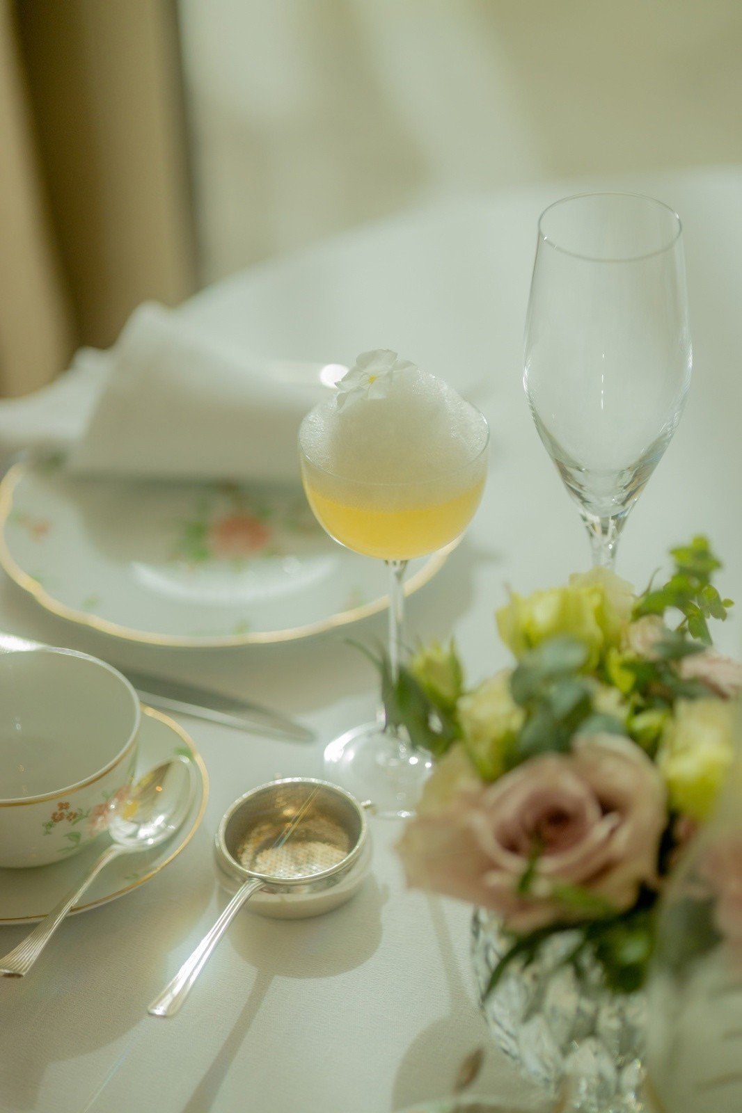 A breakfast table with a cocktail, porcelain and roses
