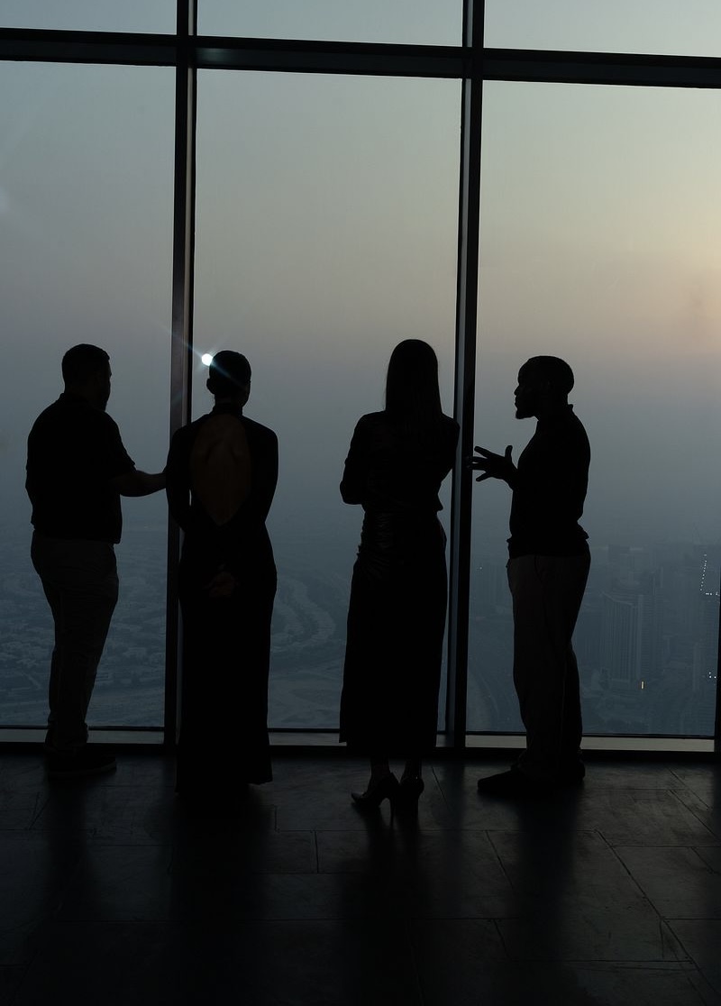 The four Beyond the Render hosts in silhouette, looking out over Dubai at dusk